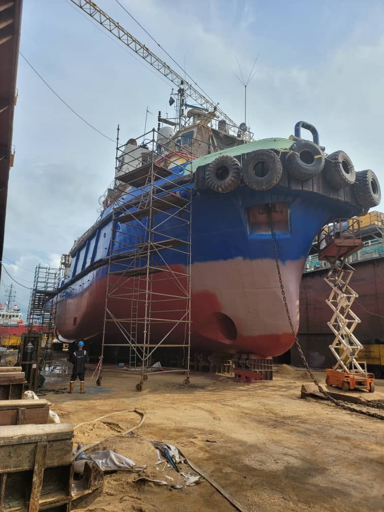 Vessel hull in dry dock with scaffolding and lift equipment