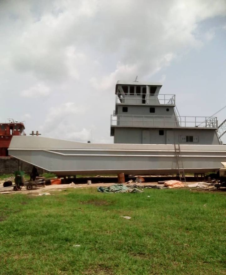 Grey tugboat hull and wheelhouse under construction in the yard