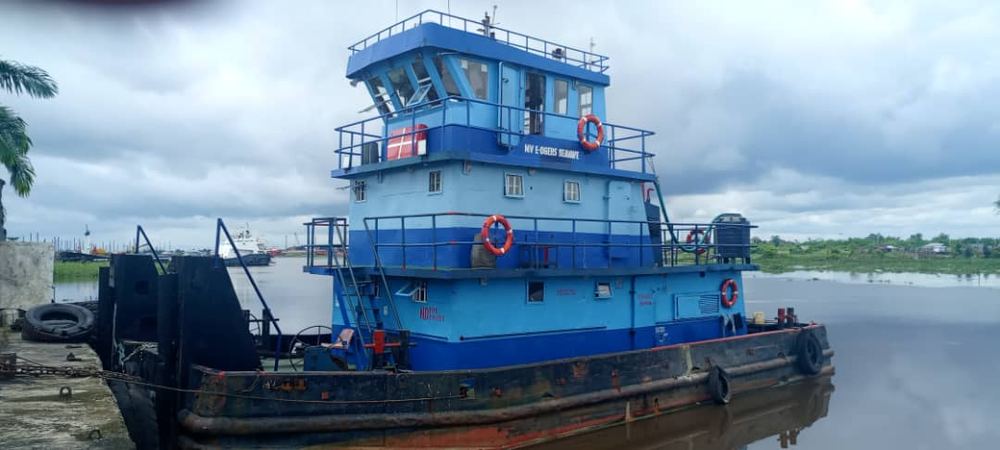 Blue and white tugboat moored at a river jetty